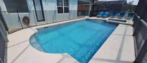Una piscina con una estructura de sombrilla, rodeada de sillas de descanso y una zona cubierta con vistas al paisaje.