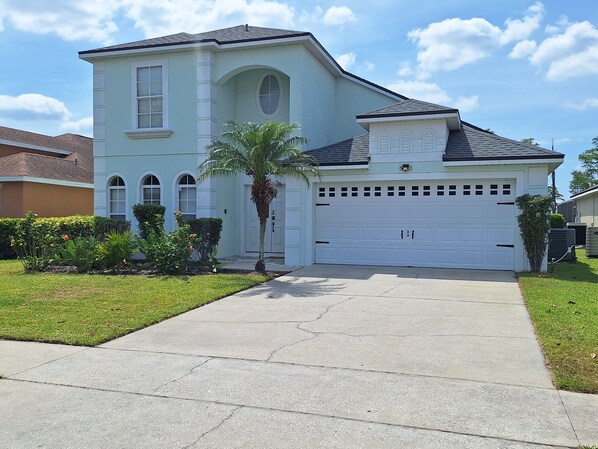 A two-story house with a garage, a driveway, and a well-maintained lawn.