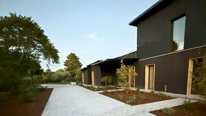 Un bâtiment moderne doté d’une allée pavée, entouré de verdure et d’arbres.