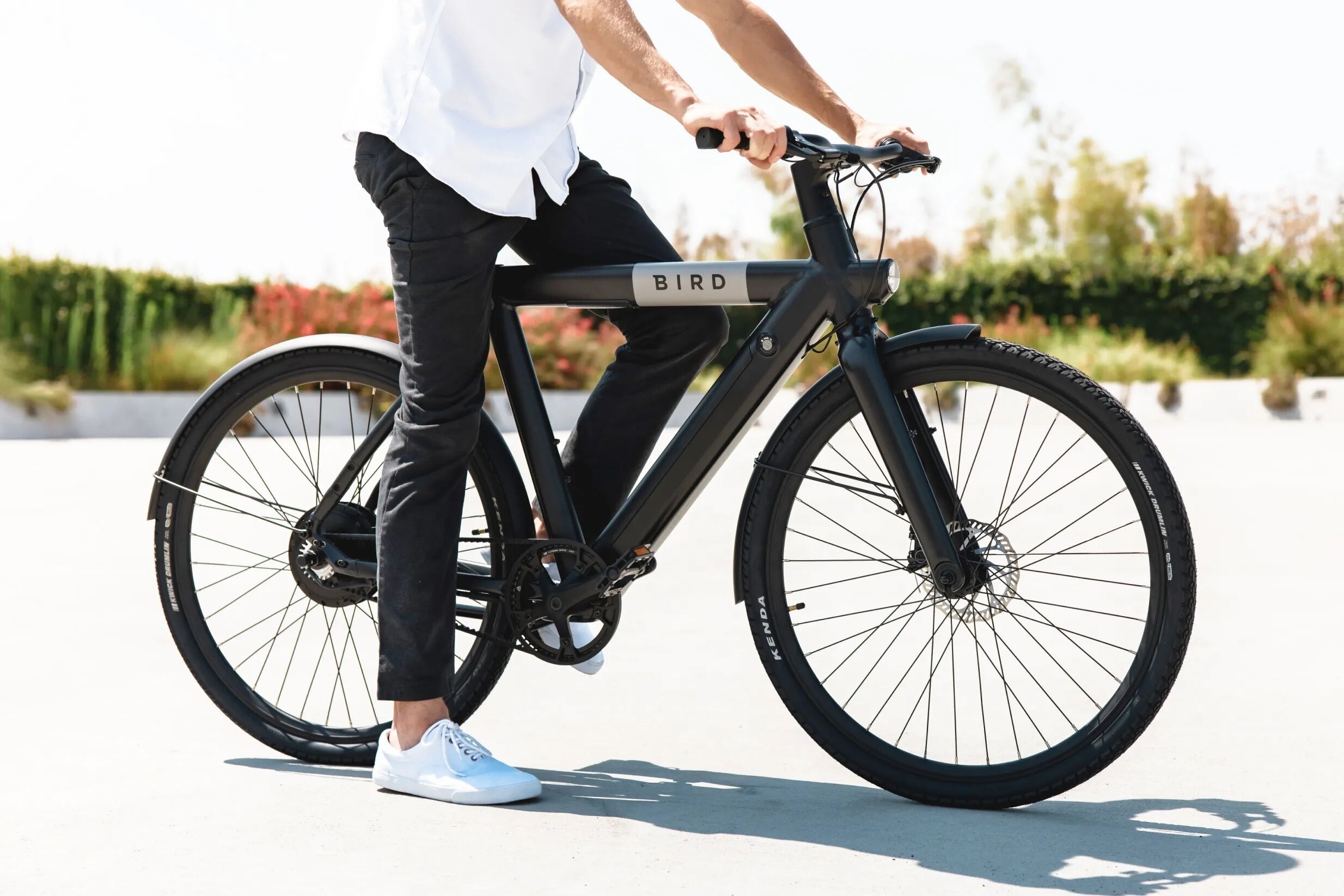 Una persona montando una bicicleta eléctrica negra con el nombre de marca 'BIRD' en el cuadro.