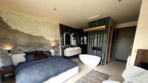 Une chambre moderne avec un grand lit, une coiffeuse intégrée et une baignoire.