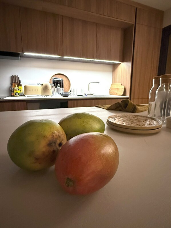 A kitchen with wooden cabinets, a countertop, and various kitchen items including a toaster, a coffee maker, and a bowl. - 537 Saint Emilion - Luxury Guest House (Saint-Laurent-des-Combes)