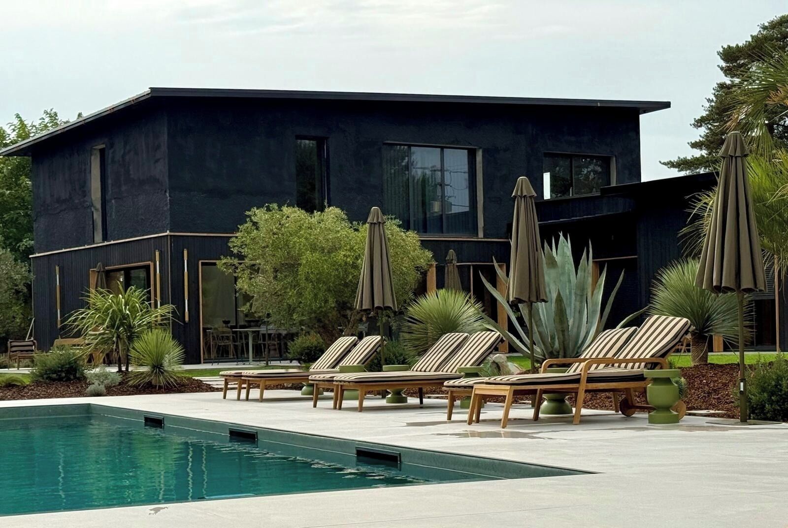 Un edificio moderno con piscina, sillas de descanso y sombrillas.