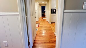 A hallway with wooden flooring, white walls, and a door leading to another room. - Secluded Farmhouse Retreat - Groups & Pets Okay! (Turkey)