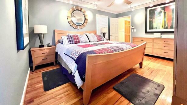 A bedroom with a wooden bed, a ceiling fan, a mirror, a dresser, and a TV on the wall. - Secluded Farmhouse Retreat - Groups & Pets Okay! (Turkey)