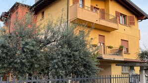 A two-story building with a balcony and a small garden area in front. - Luxury Retreat in Franciacorta (Villa Pedergnano)