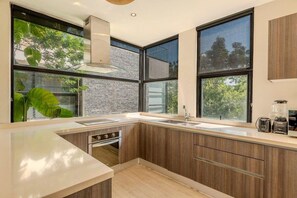 A modern kitchen with large windows, a built-in oven, and wooden cabinetry.