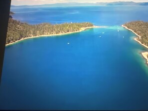 Une vue aérienne d’une zone côtière aux eaux bleues et limpides, bordée de terres boisées.