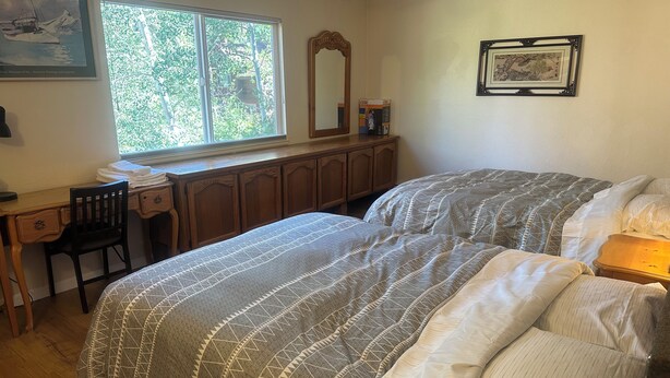A bedroom with a bed, a desk, and a window.