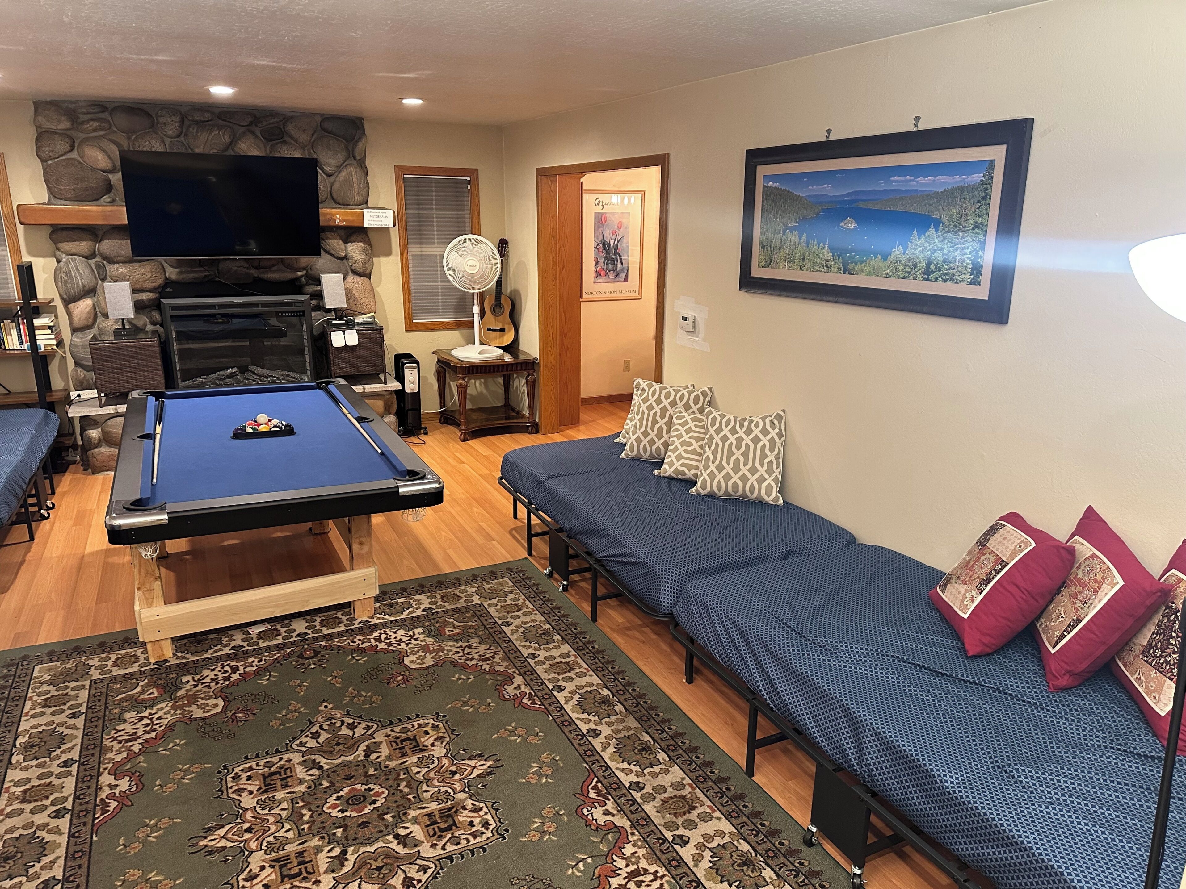 A living room with a pool table, a sofa, a fireplace, and a framed picture on the wall.