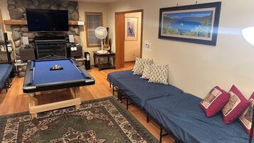 A living room with a pool table, a sofa, a fireplace, and a framed picture on the wall.