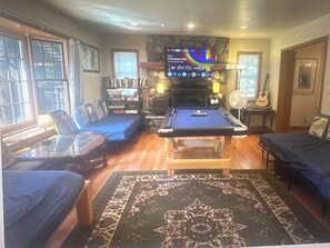Ein Zimmer mit Poolbillard, einer Couch, einem Bücherregal und einem Kamin.