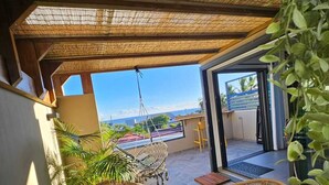 A covered outdoor seating area with wicker furniture, a small table, and potted plants. - Apartment Joly brise 4 in Terre Sainte near small beach/CHU (Saint-Pierre)
