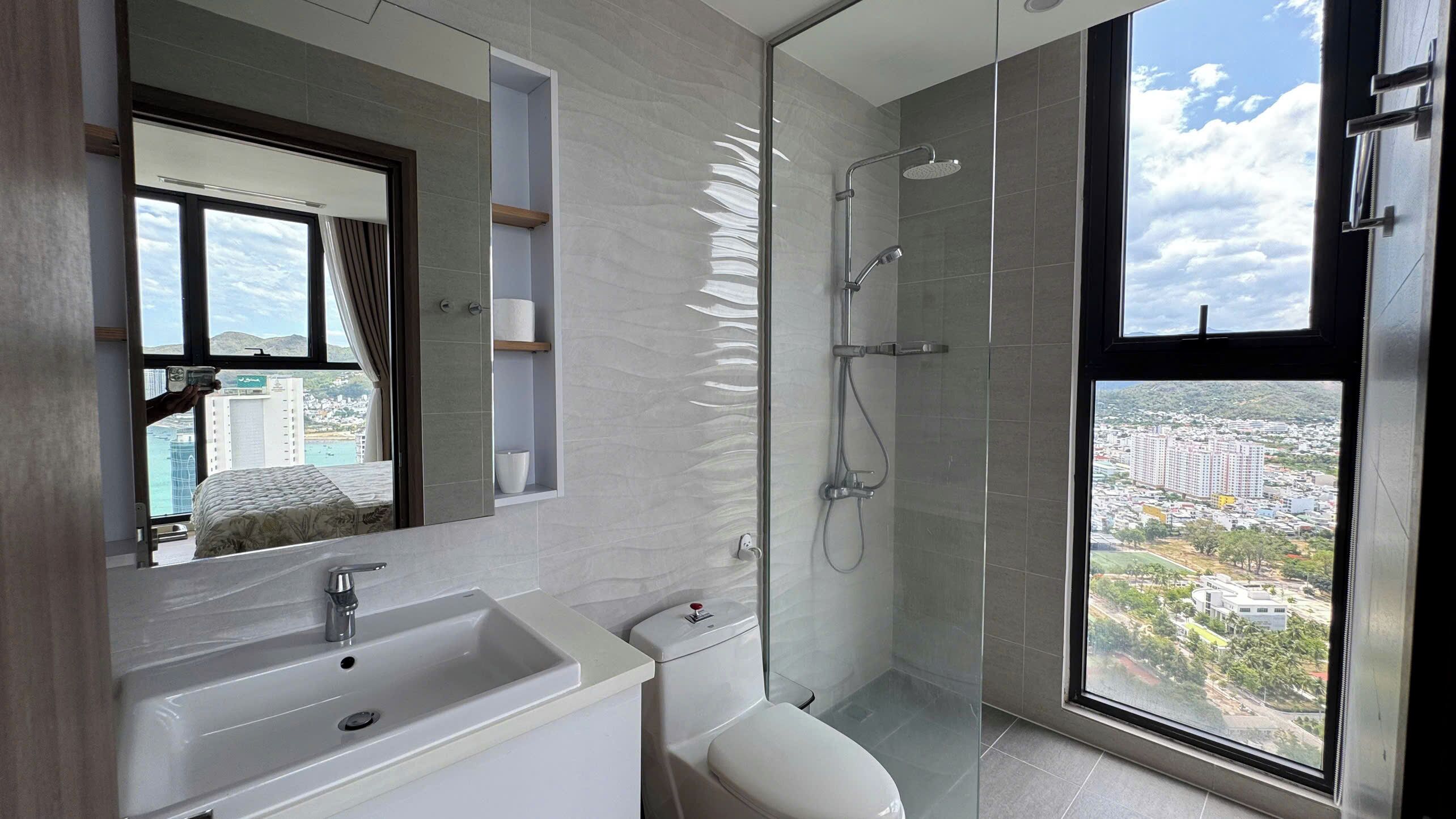 Une salle de bain moderne dotée d’une grande fenêtre, d’une douche et d’un lavabo.