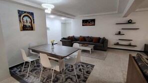 Ein modernes Wohnzimmer mit Esstisch, Sofa und dekorativen Regalen.