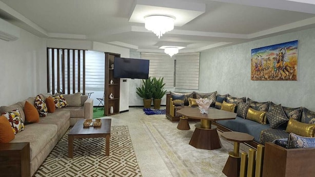 A living room with a sofa set, coffee table, TV, and a painting on the wall.