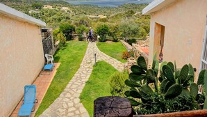 Un patio con un sendero de piedra que lleva a vistas de montañas y un lago.