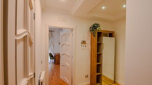 A hallway with a wooden door, a mirror, and a plant.