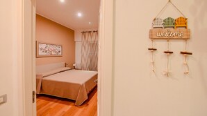 A bedroom with a bed, a 'welcome' sign, and a wall-mounted decoration.