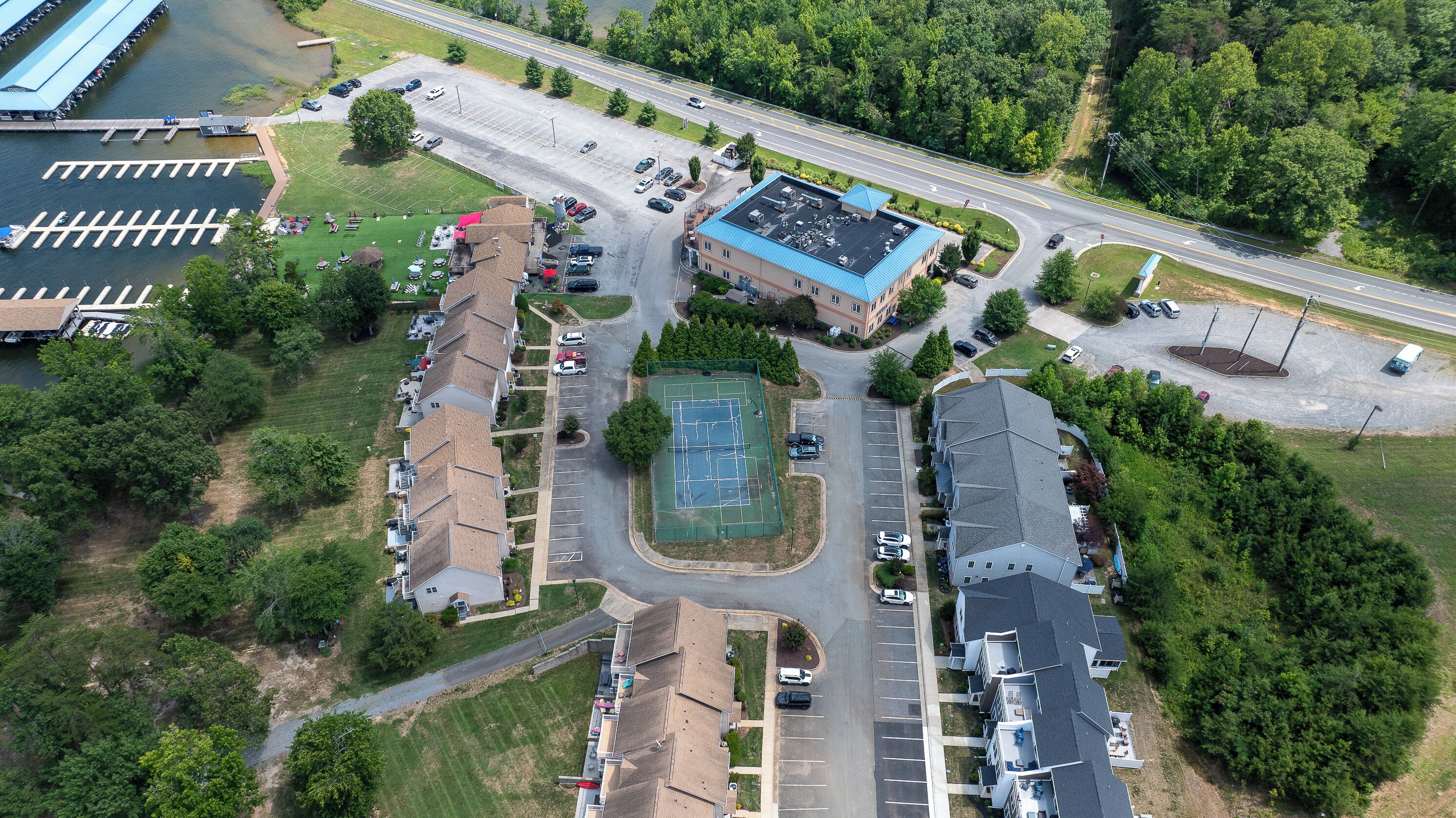 Vista aérea de una zona residencial con cancha de tenis, estacionamientos y una carretera.