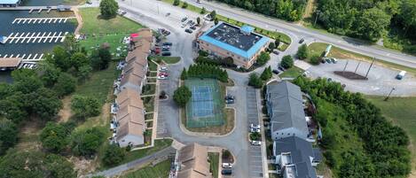 Vista aérea de una zona residencial con cancha de tenis, estacionamientos y una carretera.