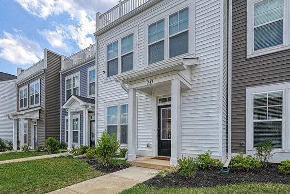 A row of townhouses with a front porch, a number '243' on the door, and a well-maintained lawn.