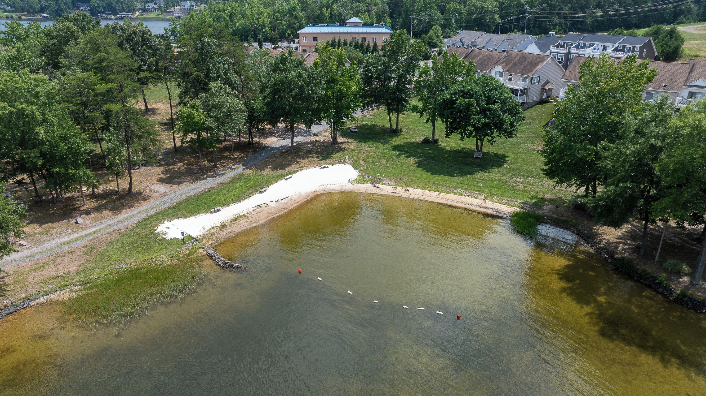 An aerial view of a residential area with a pond, surrounded by trees and houses.