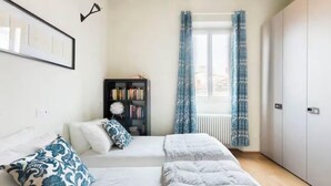 Ein modernes Schlafzimmer mit einem Bett, zwei Nachttischen, einem Bücherregal und einem Fenster mit Vorhängen.