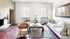 Ein Wohnzimmer mit Kamin, einer Couch, einem Couchtisch und einem Esstisch mit St ühlen.