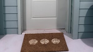 A white door with a digital lock and a doormat with shell designs. - Tranquil 2-bedroom apartment in Jacksonville (Jacksonville)