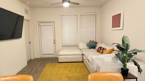 A compact living space with a ceiling fan, a sofa with cushions, a dining table with chairs, and a potted plant. - Tranquil 2-bedroom apartment in Jacksonville (Jacksonville)