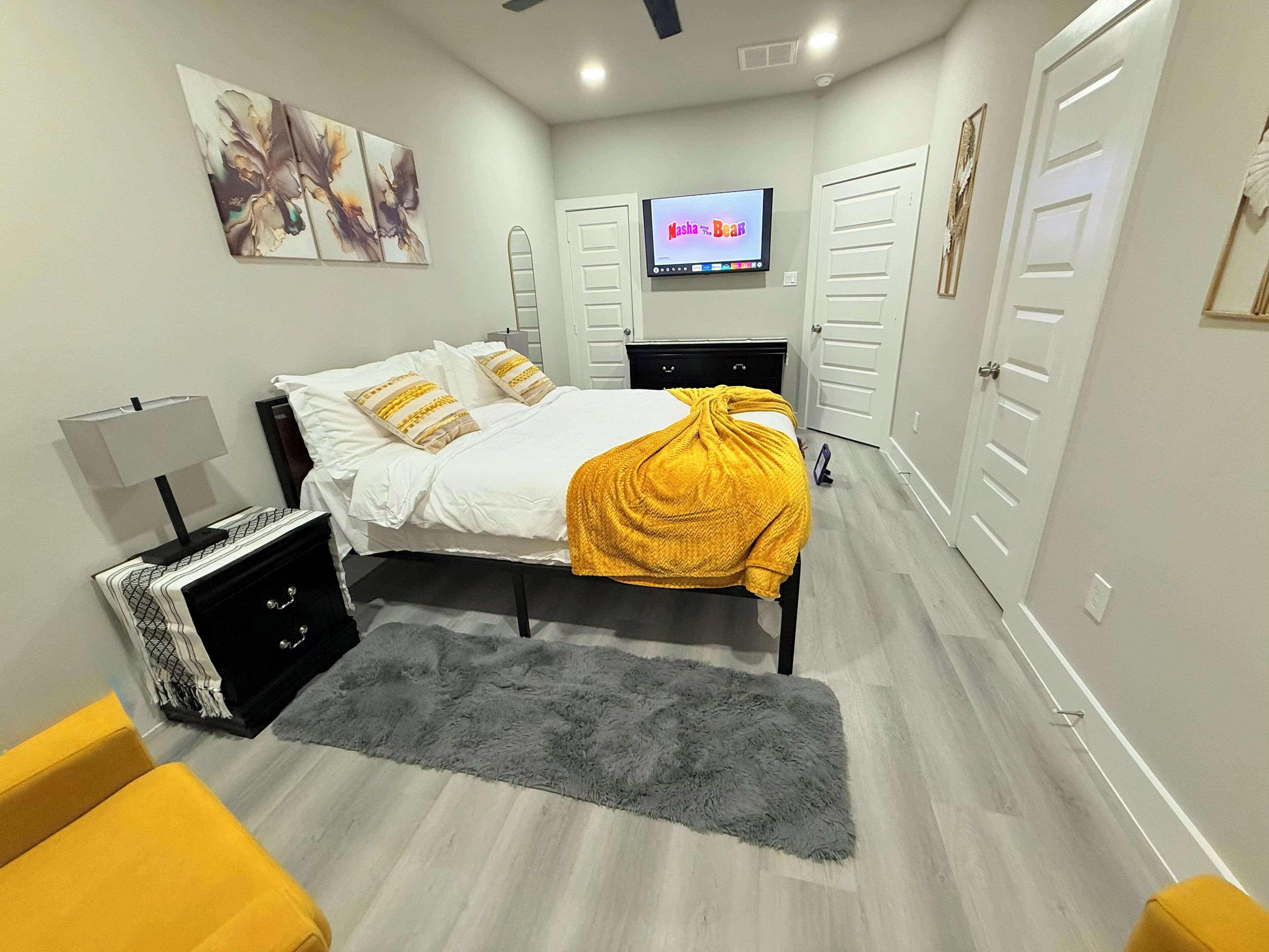 A modern bedroom with a bed, a TV, and a wardrobe.
