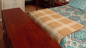 A bedroom with a bed, a wooden bench, a wardrobe, a mirror, and two bedside tables with lamps. - Charming 2-bedroom apartment in peaceful Warren with AC (Warren)