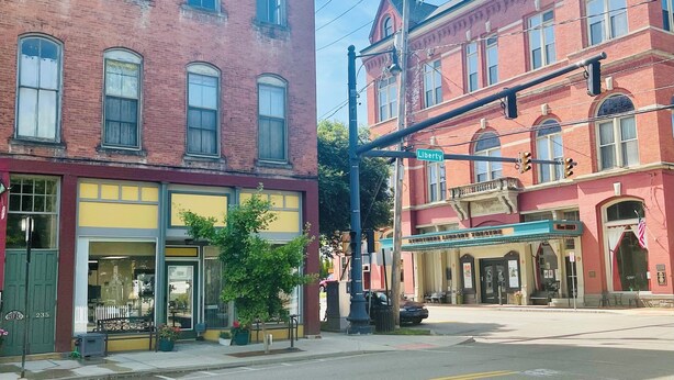 A street view with two-story brick buildings, one with a storefront and another with a library sign. - Charming 2-bedroom apartment in peaceful Warren with AC (Warren)