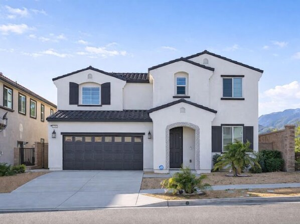 A two-story house with a garage, a small porch, and a landscaped front yard.