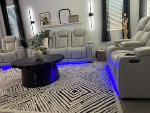 Un salon moderne avec un canapé d’angle, une table basse noire et un tapis à motifs.