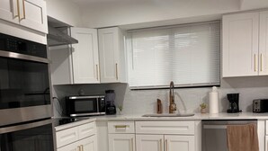 A modern kitchen with white cabinetry, stainless steel appliances, and a marble floor. - Casa Del Encanto, Beautiful home 5 minutes from  Wynwood Design destrict (Miami)