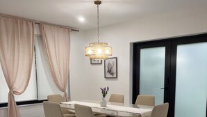 A dining area with a table, chairs, a chandelier, and a large window with curtains. - Casa Del Encanto, Beautiful home 5 minutes from  Wynwood Design destrict (Miami)