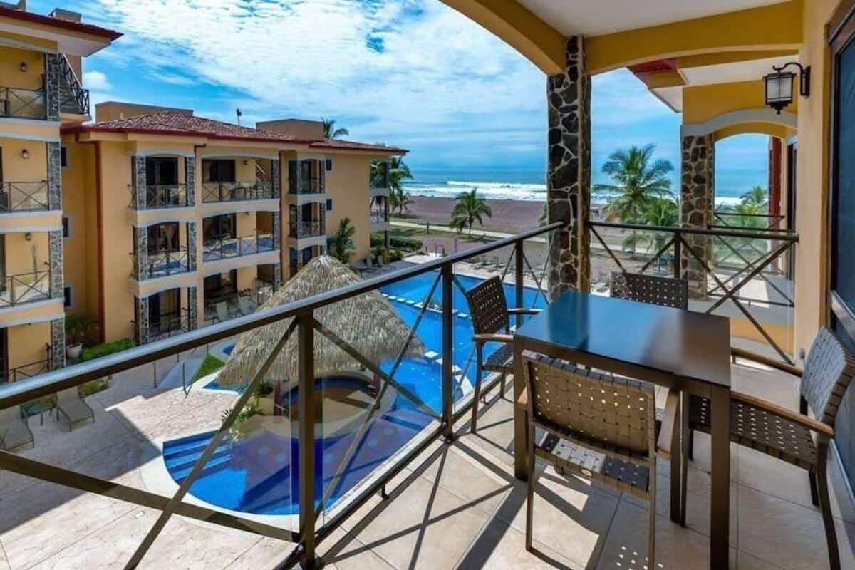 A balcony with a pool, overlooking a beach and ocean.
