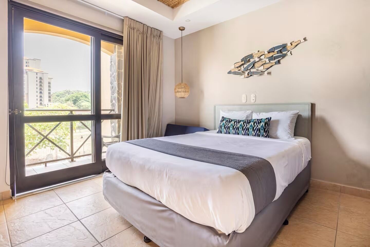 Ein Hotelzimmer mit einem großen Bett, Blick durch eine Glastür und einer modernen Wanddekoration.