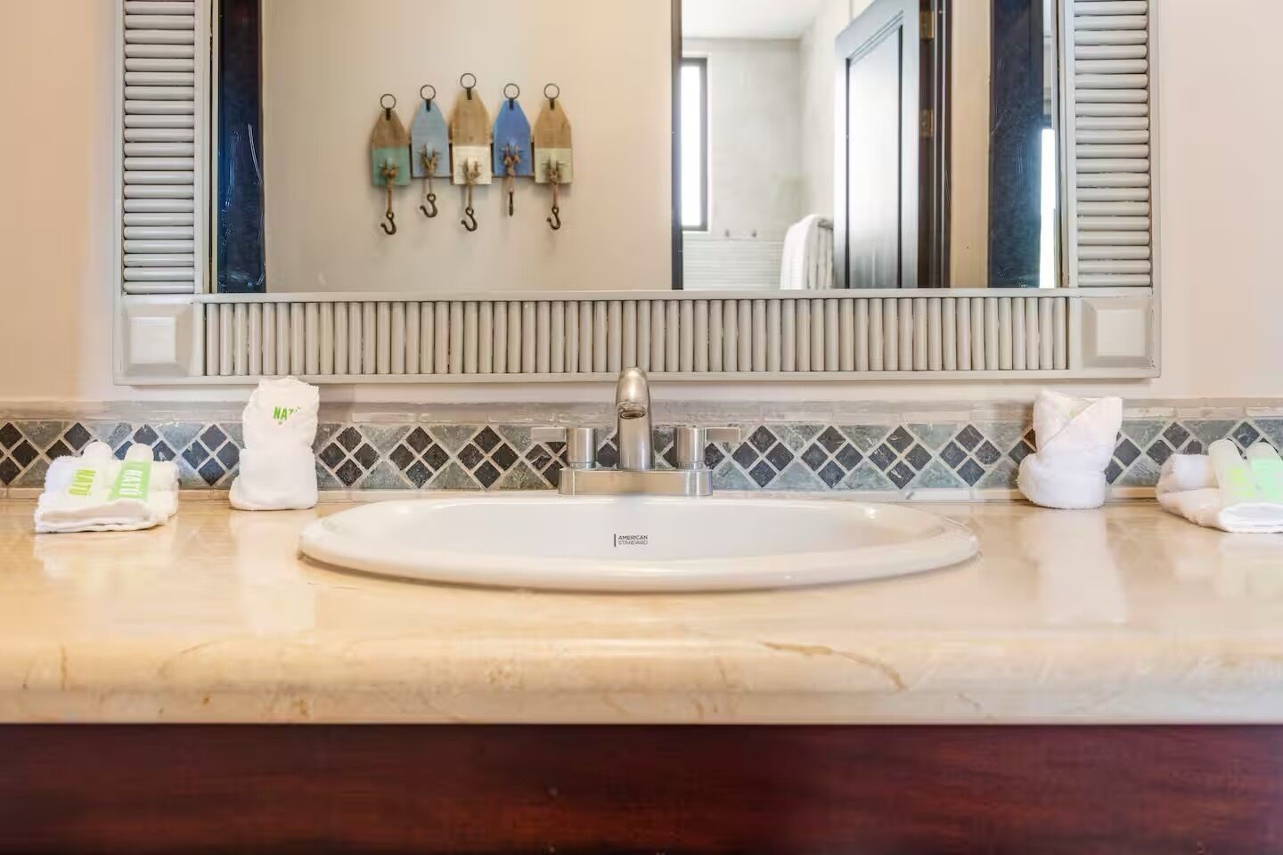 Un baño con un espejo grande, un lavabo y un perchero con adornos.