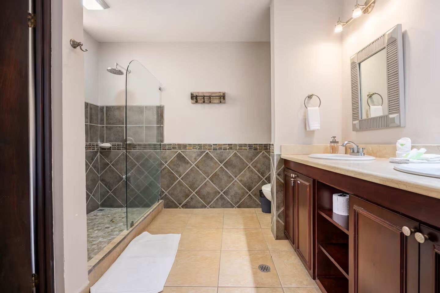 A bathroom with a glass shower enclosure, a vanity with a mirror, and a tiled backsplash.