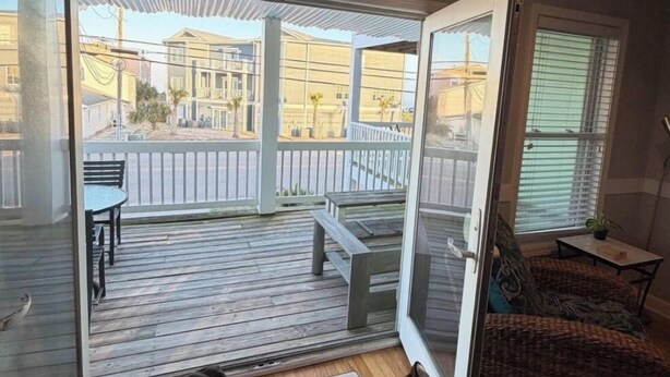 Una habitación con puerta de vidrio corrediza que da a una terraza exterior con banco y mesa.
