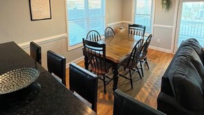 Un comedor con una mesa y sillas de madera, encimera negra y ventilador de techo.