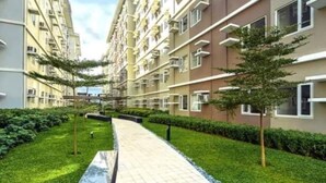 A modern apartment building with a central pathway, surrounded by well-maintained greenery and trees. - Live the Dream in the Heart of Quezon City! Your Perfect 1-BHK Apartment Awaits. (Quezon City)