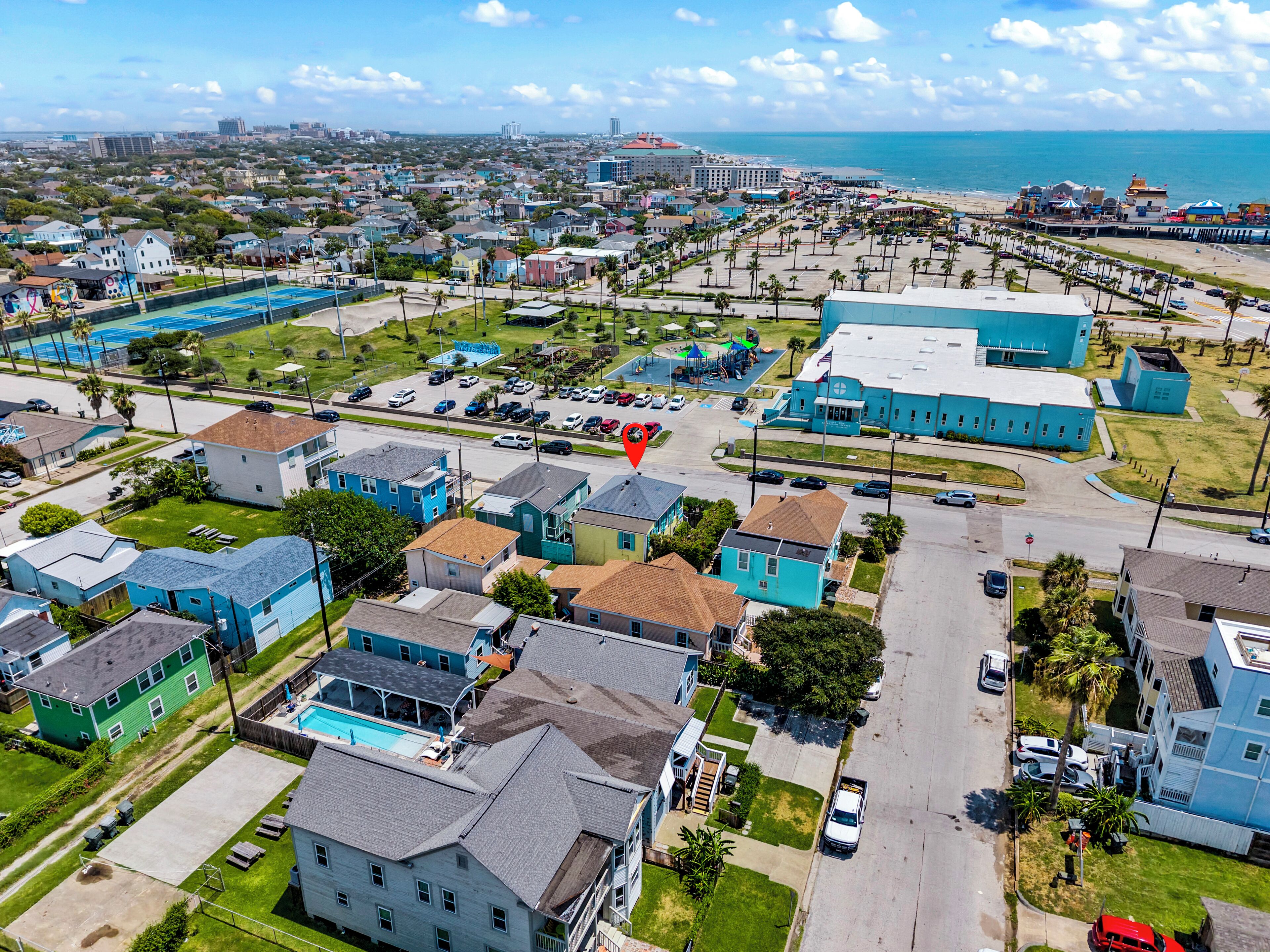 Vista aérea de un pueblo costero con edificios residenciales, una playa y un puerto deportivo.