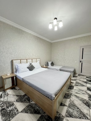 A bedroom with a large bed, two bedside tables, a nightstand, and a wardrobe. - Chaqar 198 (Tashkent)