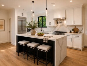 A modern kitchen with a central island, bar stools, a stainless steel refrigerator, and a stove. - Gated Santa Barbara Villa, Walk to Hendry's Beach, with Private Casita (Santa Barbara)