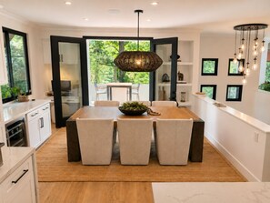 A modern kitchen with white cabinets, a wooden dining table, and a hanging light fixture. - Gated Santa Barbara Villa, Walk to Hendry's Beach, with Private Casita (Santa Barbara)