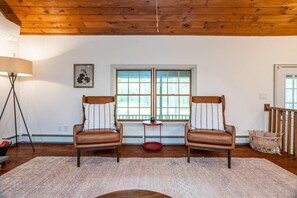 Une pièce comprenant deux fauteuils en cuir, une petite table, un lampadaire et une fenêtre donnant sur un beau paysage.